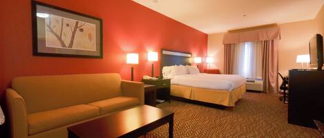 A hotel room with a bed, a sofa, a desk, and a TV.