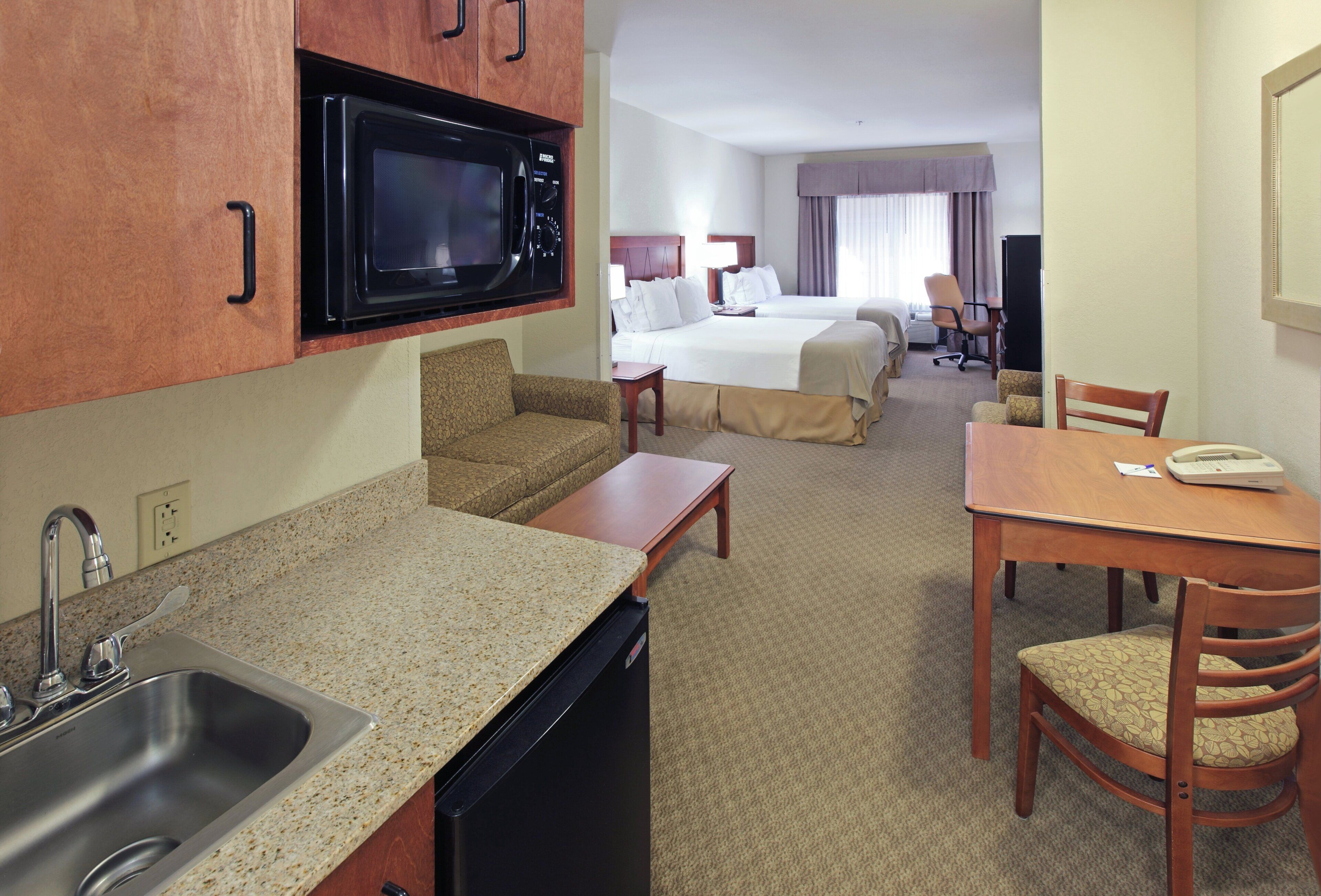 Une chambre d’hôtel équipée d’une kitchenette, d’un lit, d’un bureau et d’une chaise.