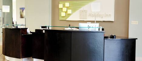 A reception desk with a modern design, a large wall sign, and a glass partition.