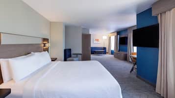 Una habitación de hotel con una cama grande, un escritorio, una silla, un televisor y un sofá.