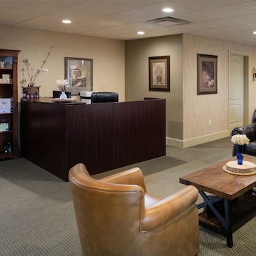 A hotel lobby with a reception desk, leather sofas, a coffee table, and framed artwork on the walls.