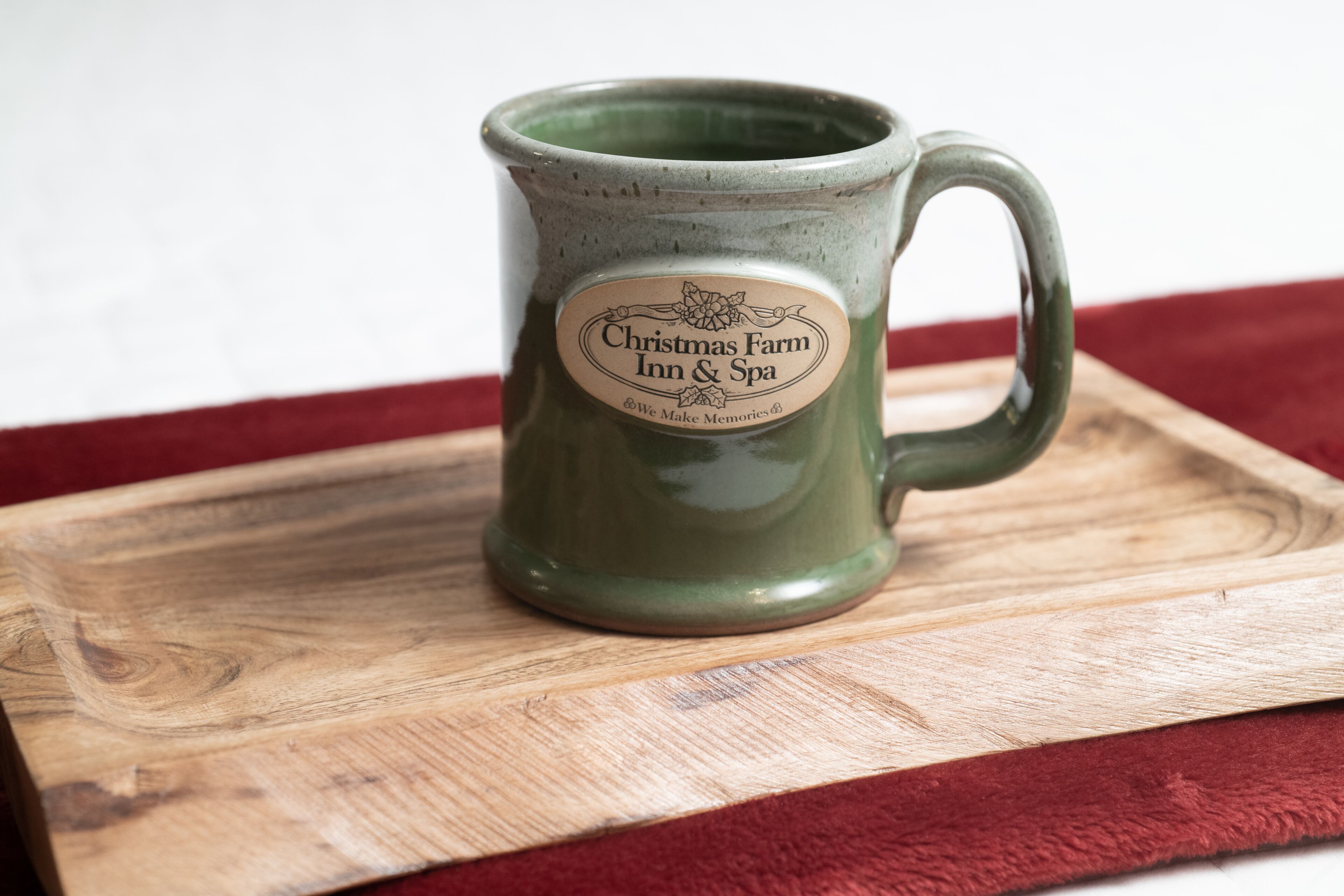 A green ceramic mug with a label on a wooden tray.