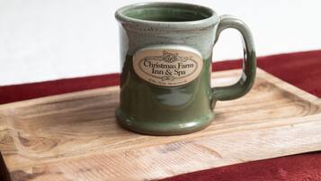 Una taza de cerámica verde con una etiqueta sobre una bandeja de madera.