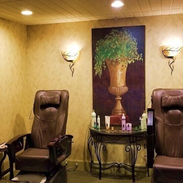 A room with two leather chairs, a table with bottles, and a painting of a vase with a tree.