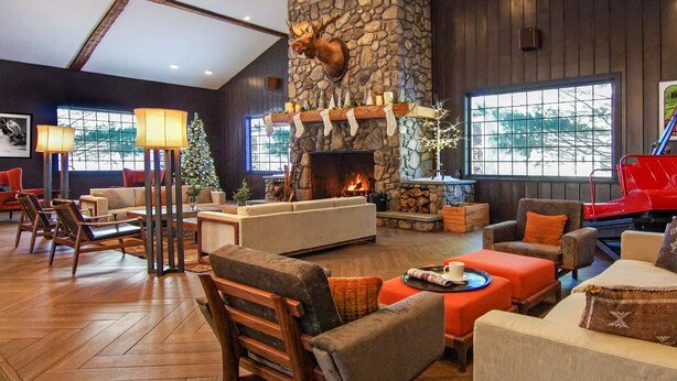 A cozy living room with a stone fireplace, comfortable seating, and a Christmas tree. - The Green Granite North Conway, an Ascend Collection Hotel (North Conway)