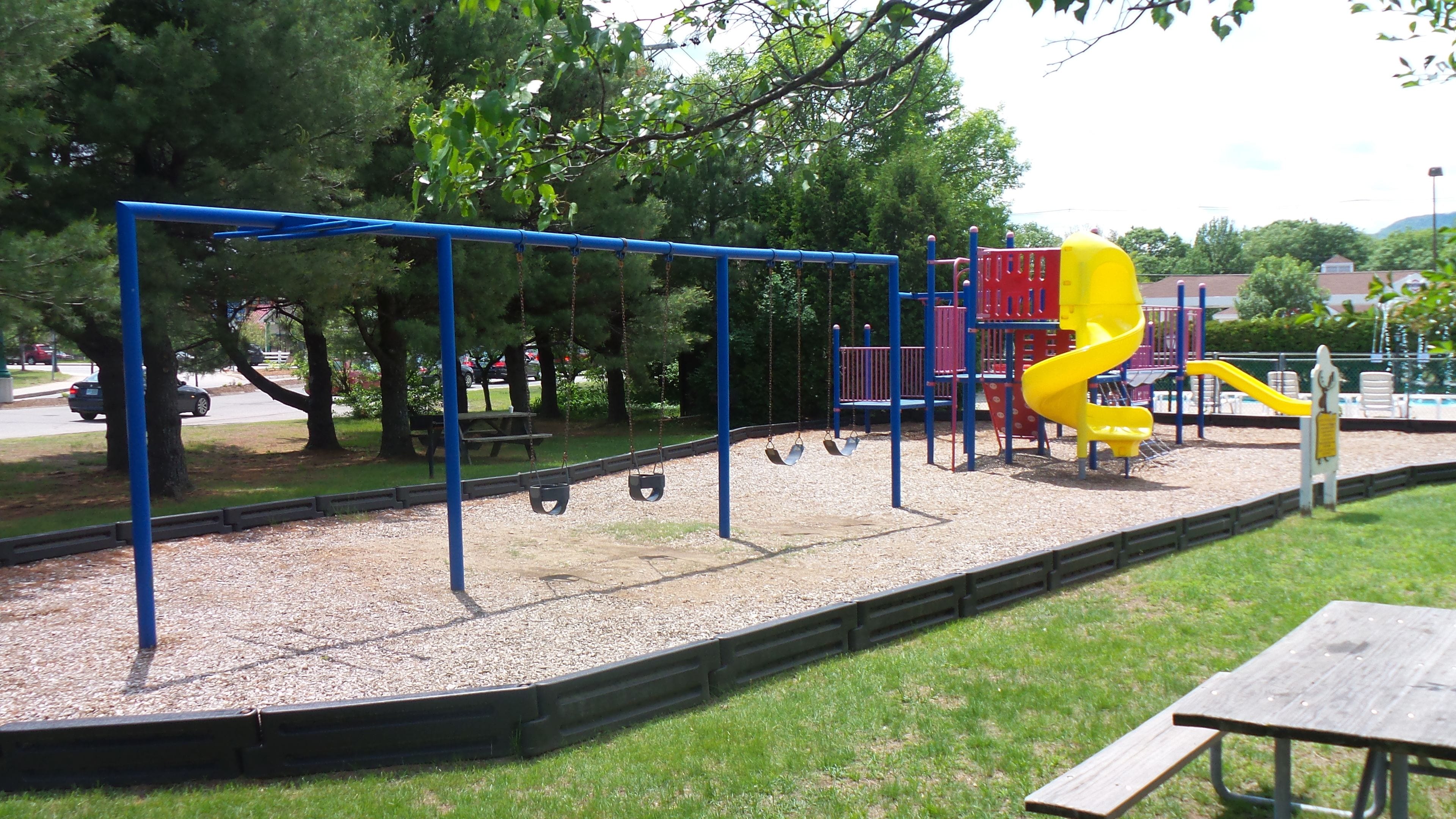 A playground with swings, a slide, and a picnic table.