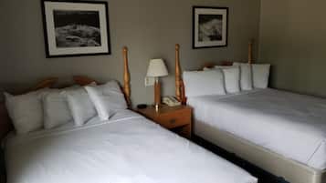 Una camera d'albergo con due letti, ognuno con biancheria bianca e testate in legno. Sono presenti due comodini con lampade e un telefono.