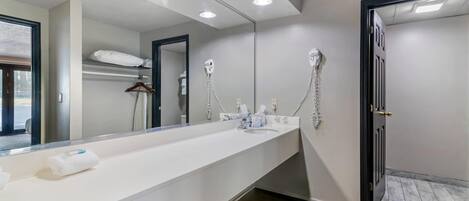 A modern bathroom with a long vanity, a large mirror, and a shower area.
