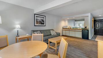 A modern living room with a dining table, sofa, and kitchen area.