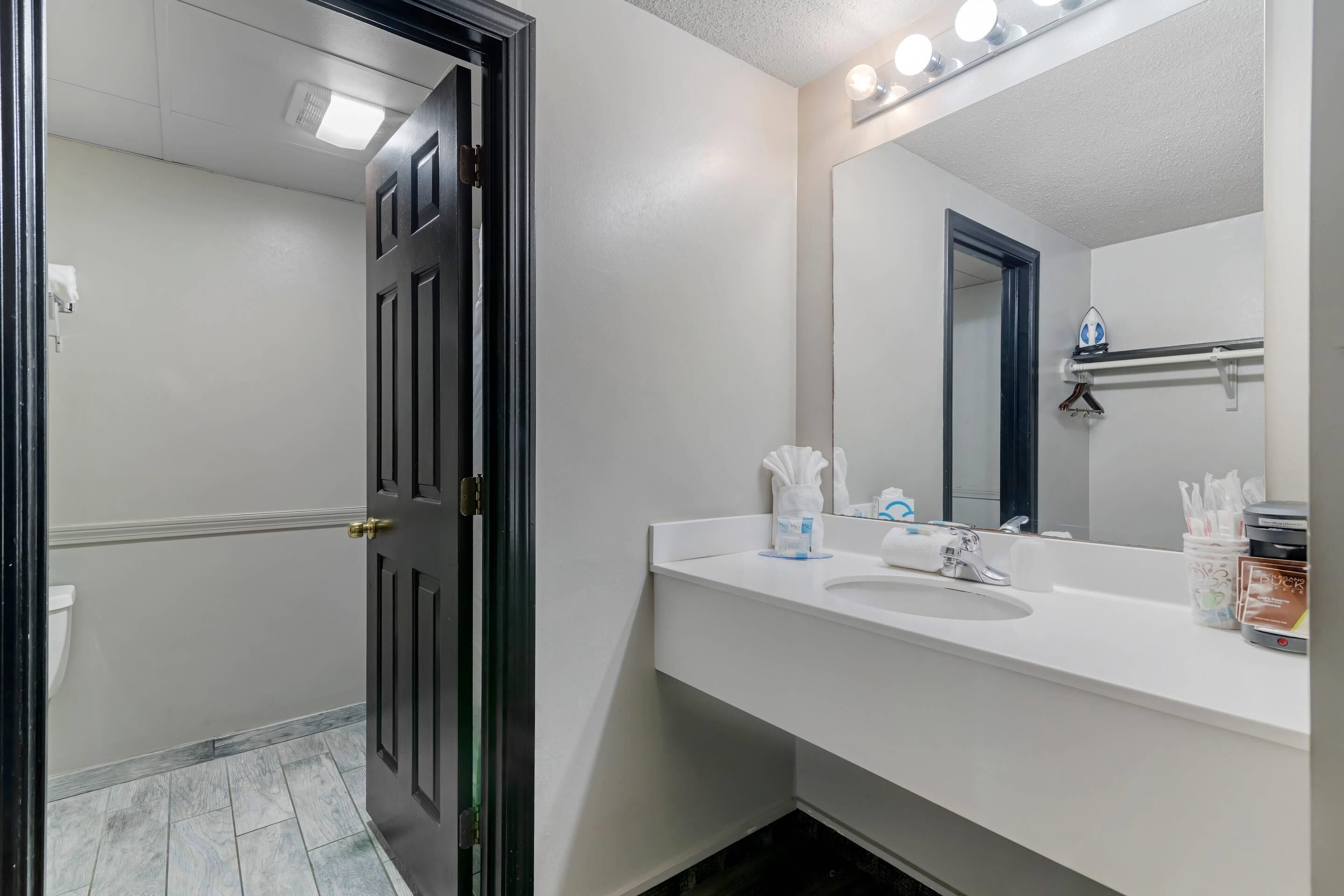 Une salle de bain avec un lavabo blanc, un miroir et un distributeur de serviettes.