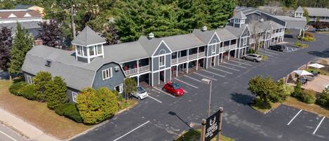 A motel with a parking lot, a covered walkway, and a view of a mountain range.