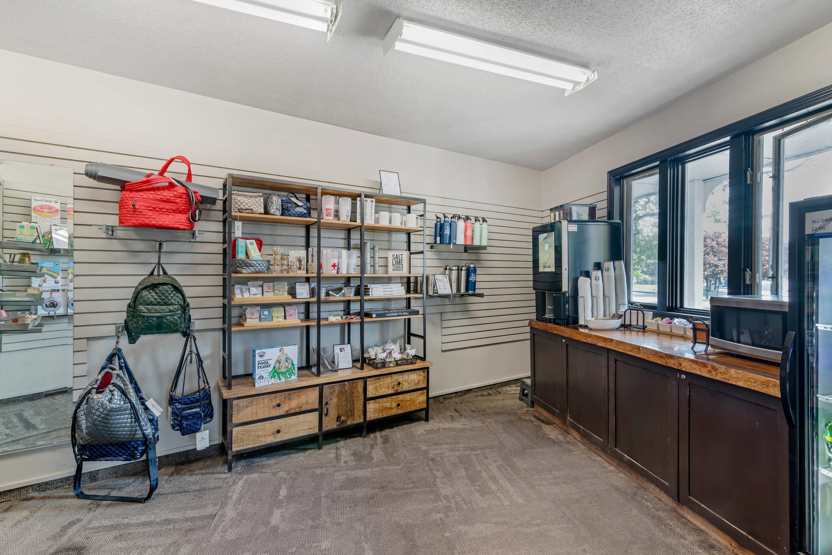 A retail space with shelves stocked with various products, a display counter, and a coffee machine.