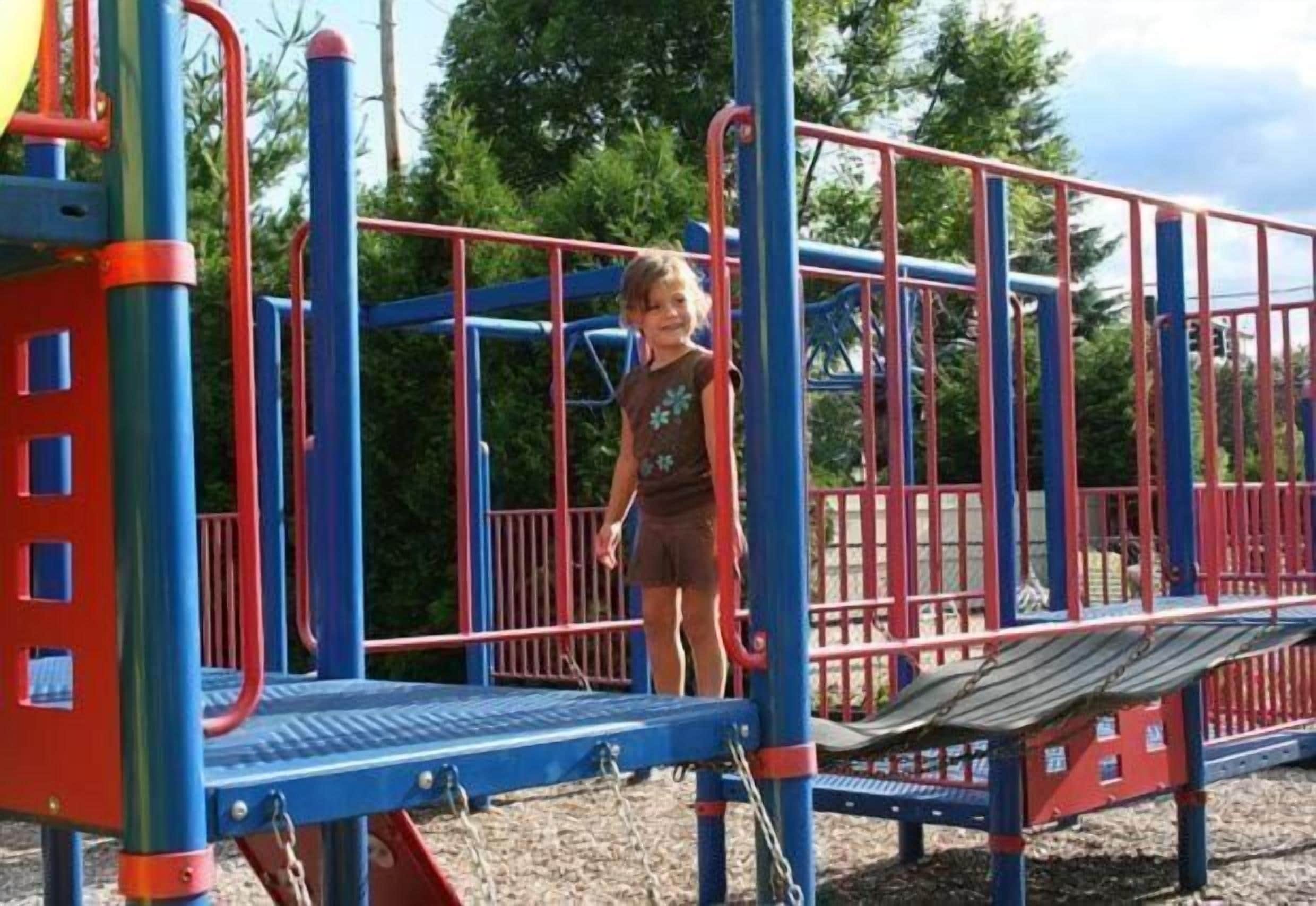 Un parque infantil con tobogán, estructuras para escalar y una paleta de colores rojo y azul.