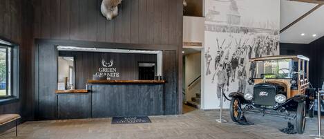 A reception area with a mounted deer head, a Ford Model T car, and a wall with black and white photographs.