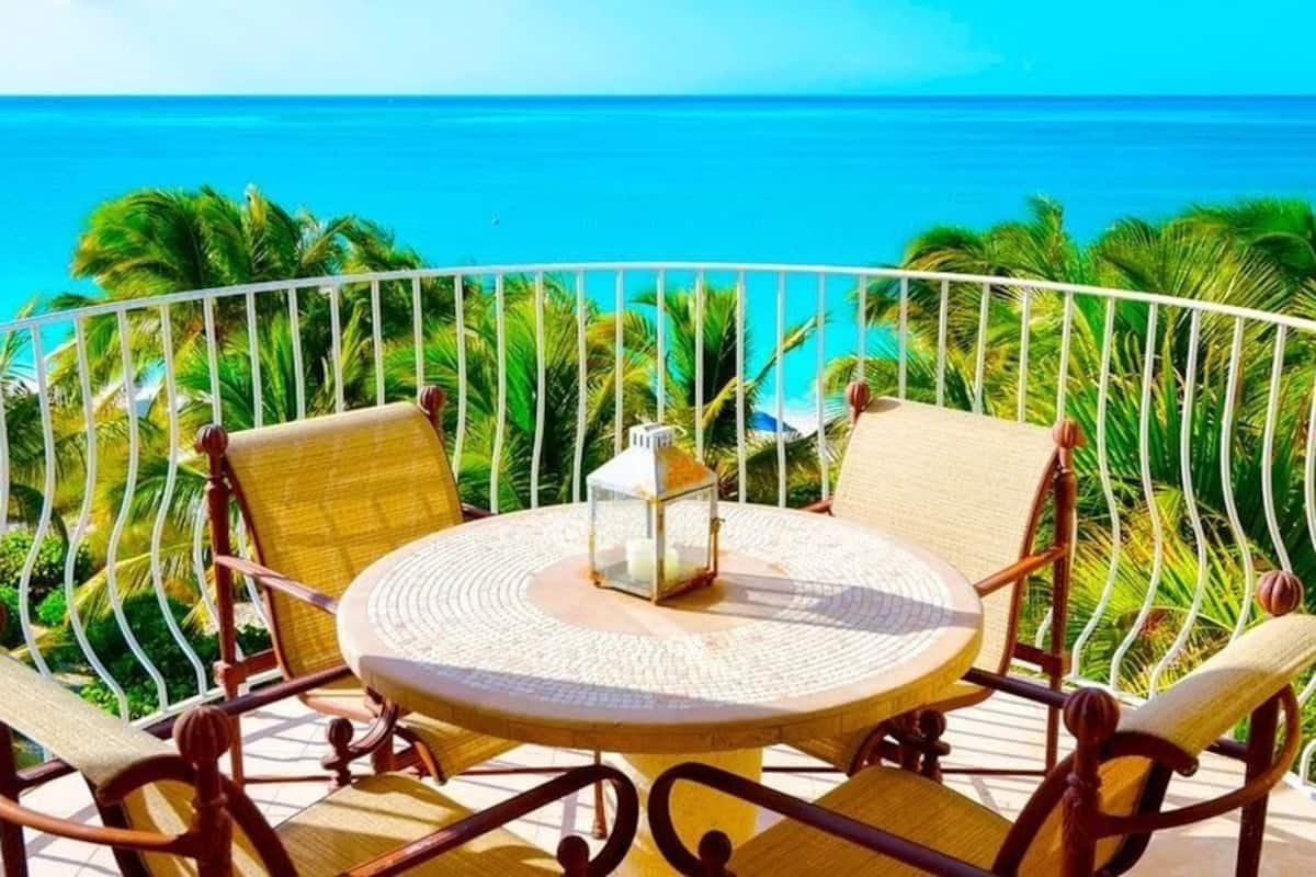 Ein runder Tisch mit vier Stühlen auf einem Balkon mit Meerblick.