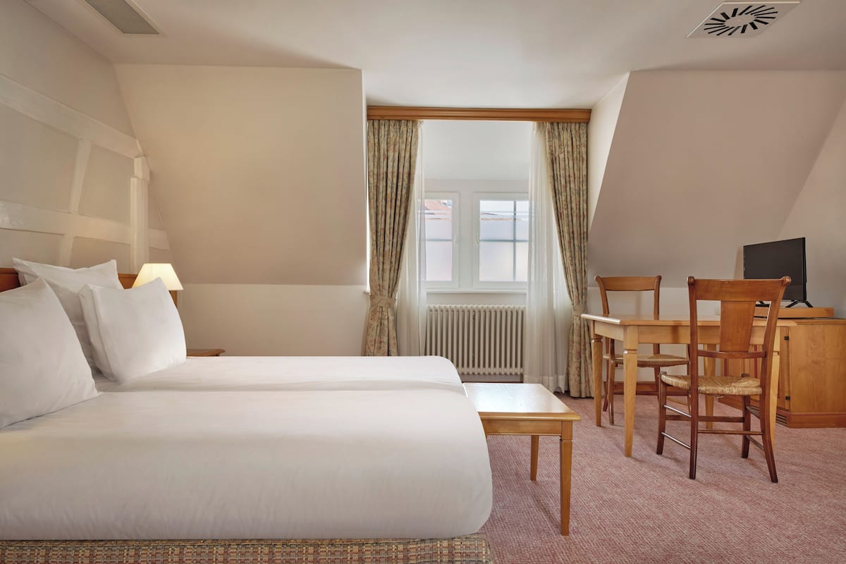 Habitación de hotel con dos camas, un escritorio y una silla.