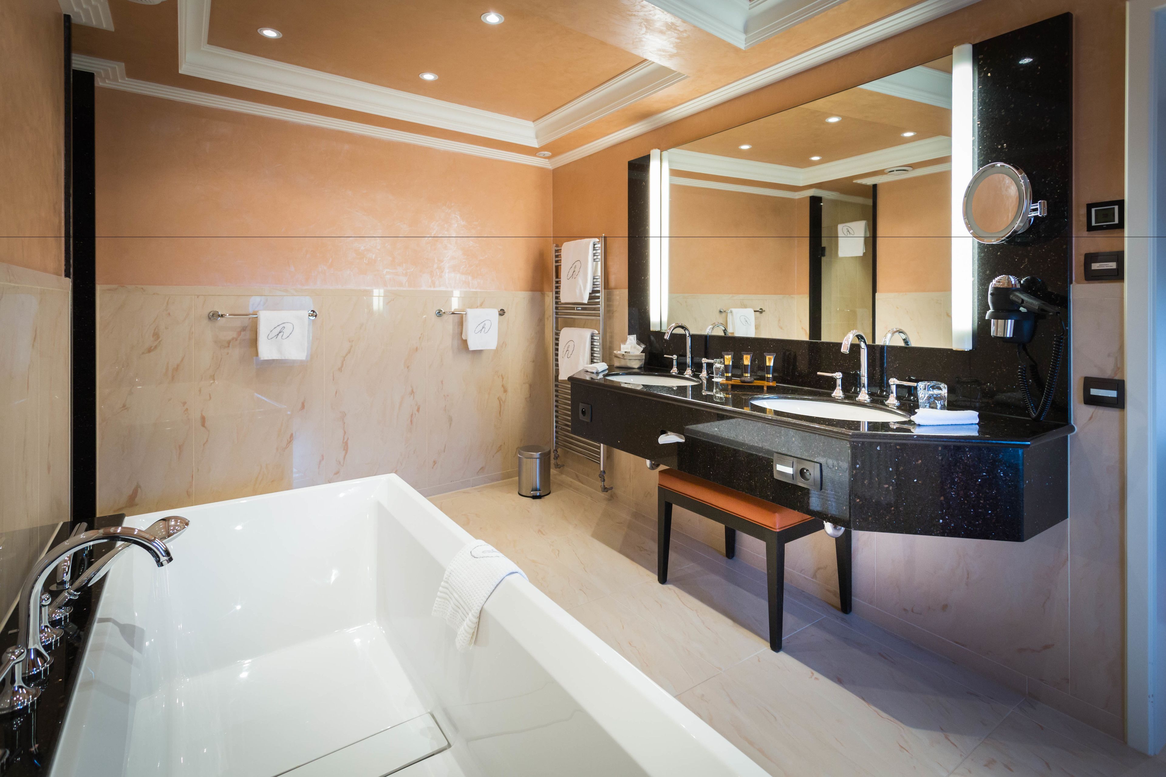 Une salle de bain moderne avec une grande baignoire, un meuble-lavabo doté d’un plan de travail noir et un miroir au-dessus du lavabo.