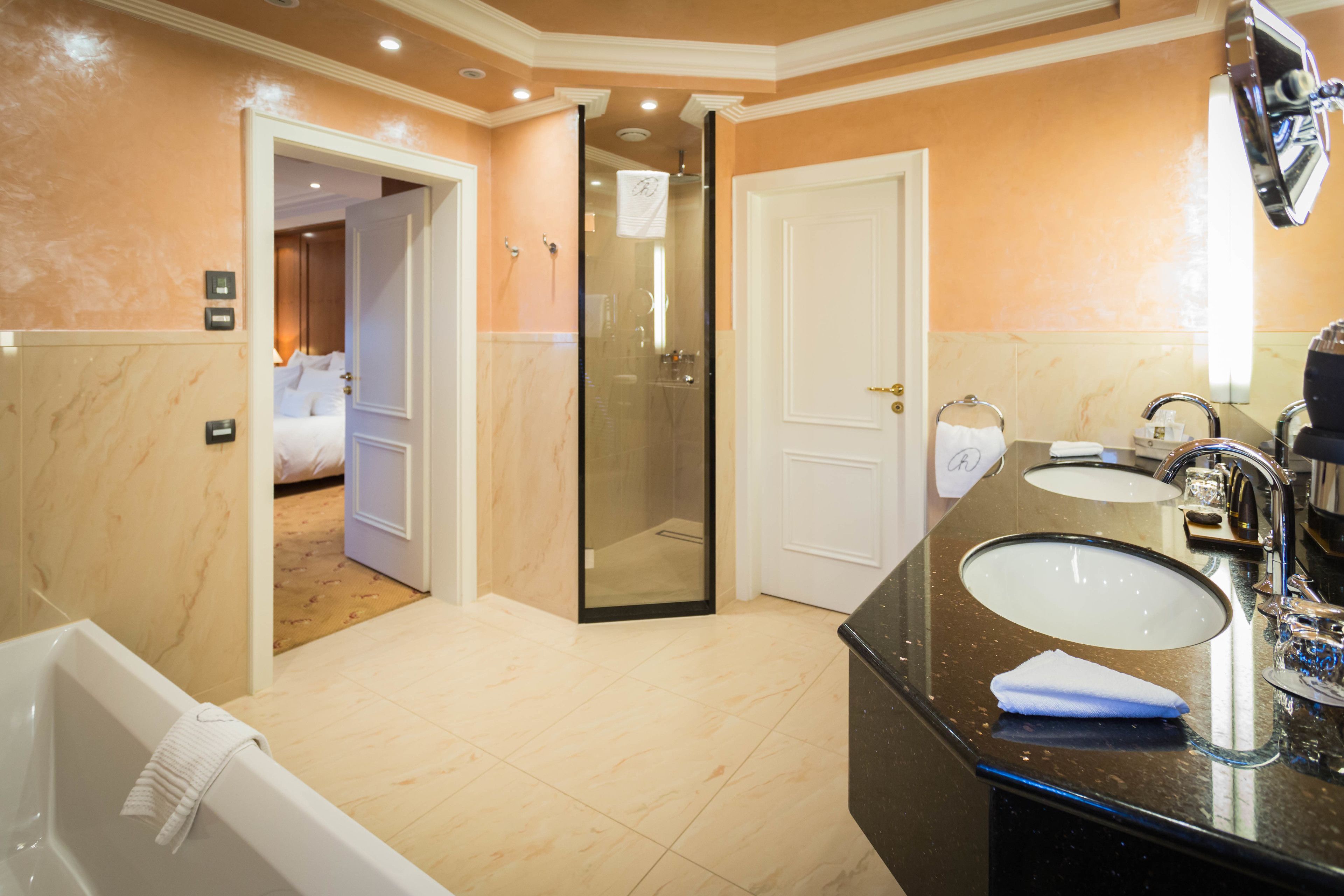 A modern bathroom with a bathtub, two sinks, and a walk-in shower.