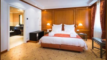 Habitación de hotel con una cama grande, dos mesitas de noche con lámparas, una mesita pequeña y un espejo.