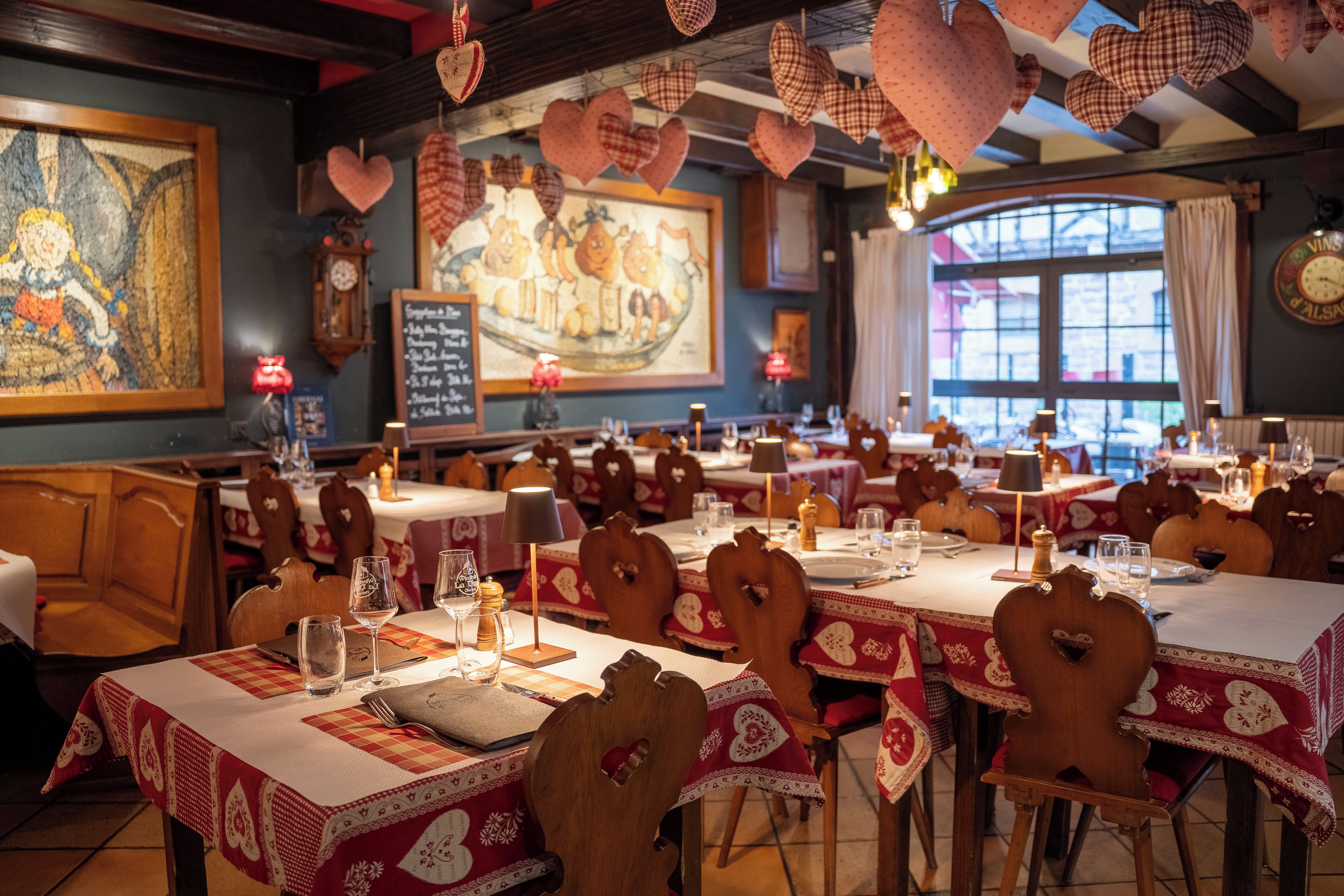 Un restaurante con varias mesas, decoraciones con forma de corazón y un cuadro grande en la pared.