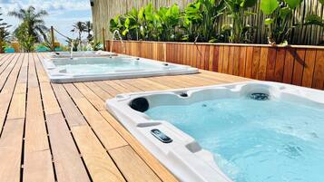 A wooden deck with two hot tubs and a bamboo fence.