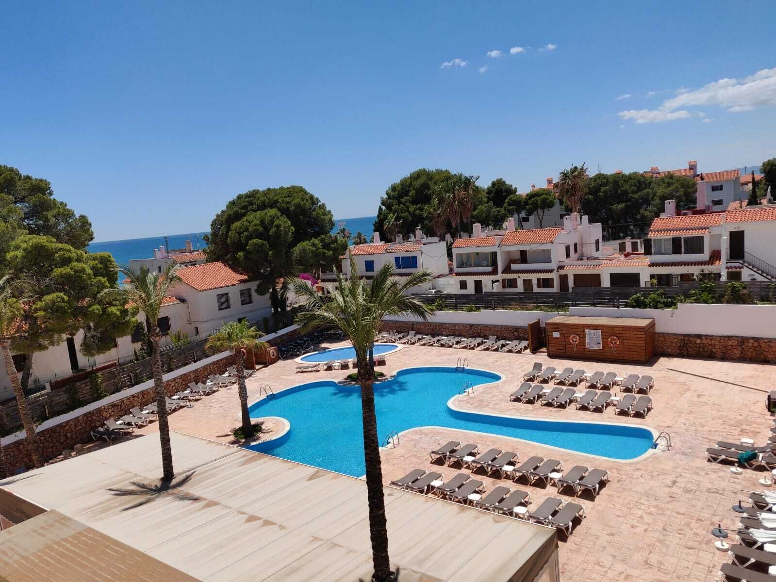A resort with a pool area, lounge chairs, and a view of the sea.
