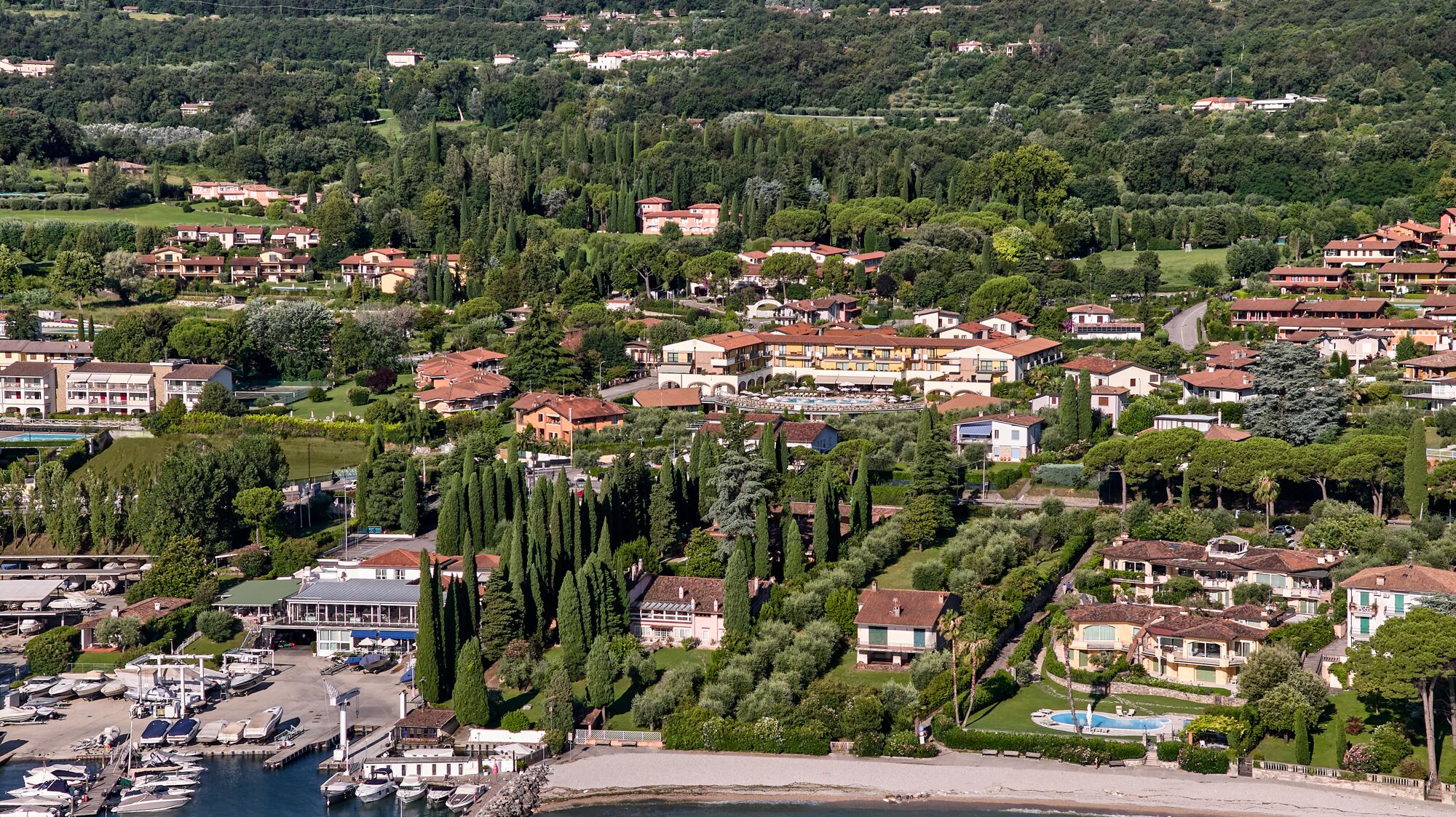 A coastal town with residential buildings, a marina, and a beach.