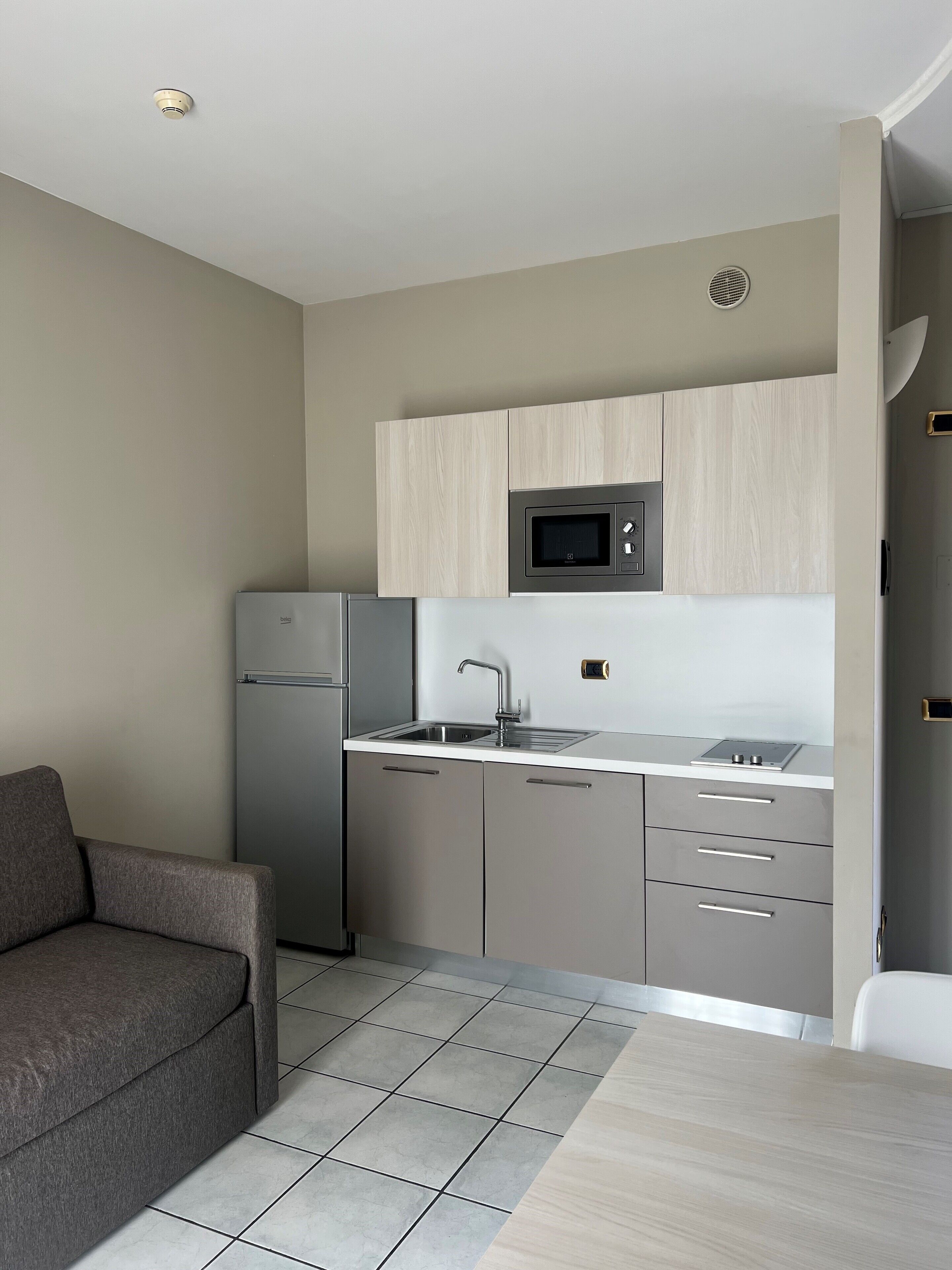 A compact kitchen with a refrigerator, microwave, sink, and cabinets.