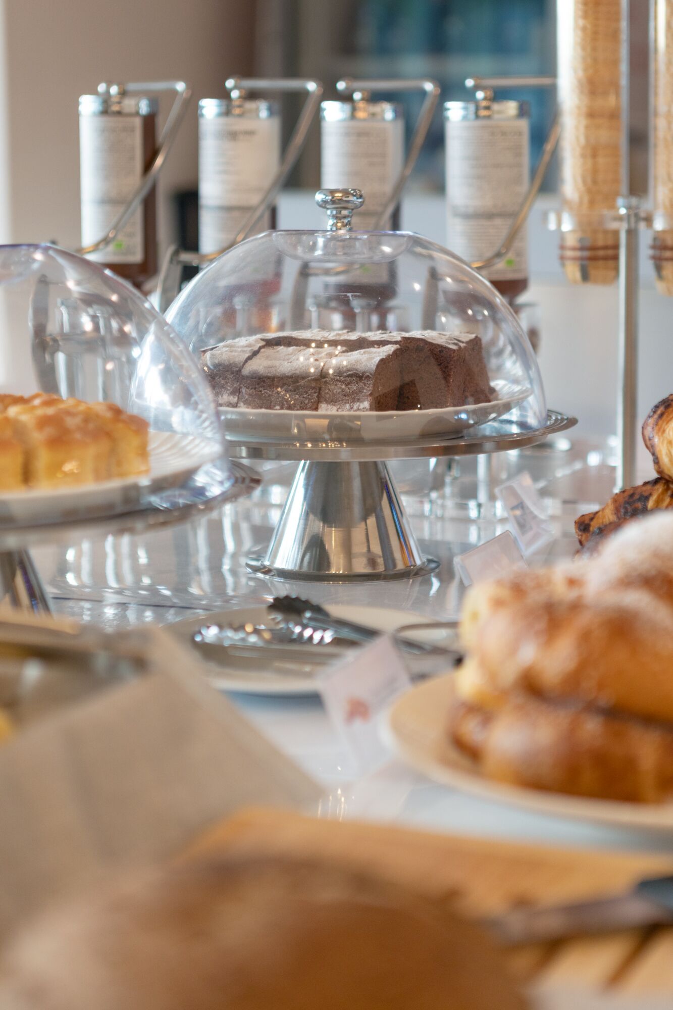 A dessert display with various cakes and pastries under glass domes.