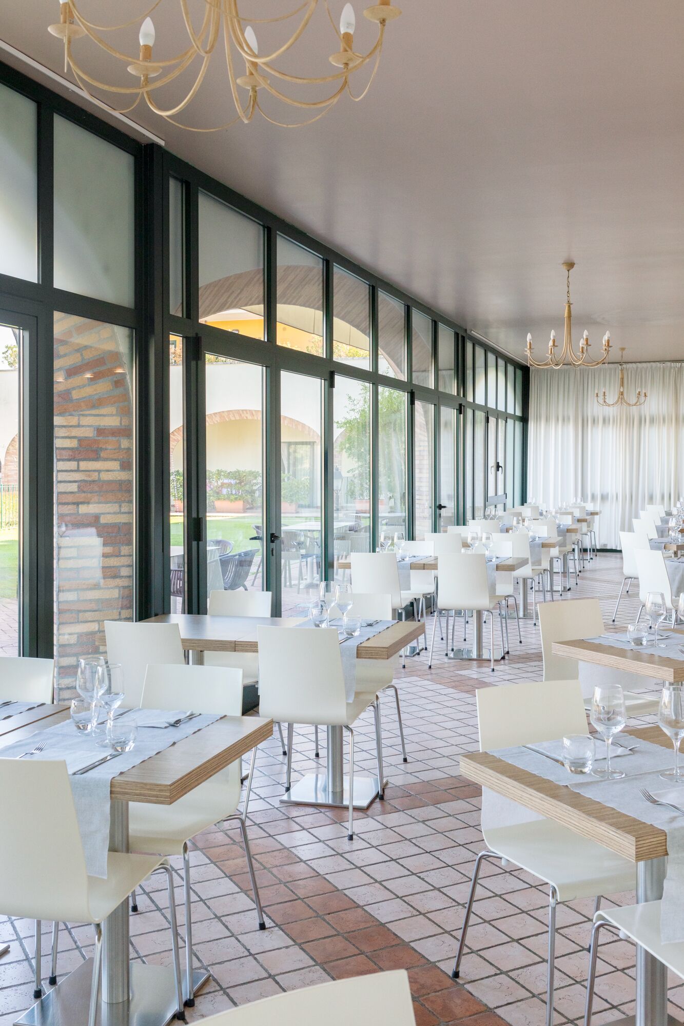 Un restaurante con varias mesas, sillas y una araña.