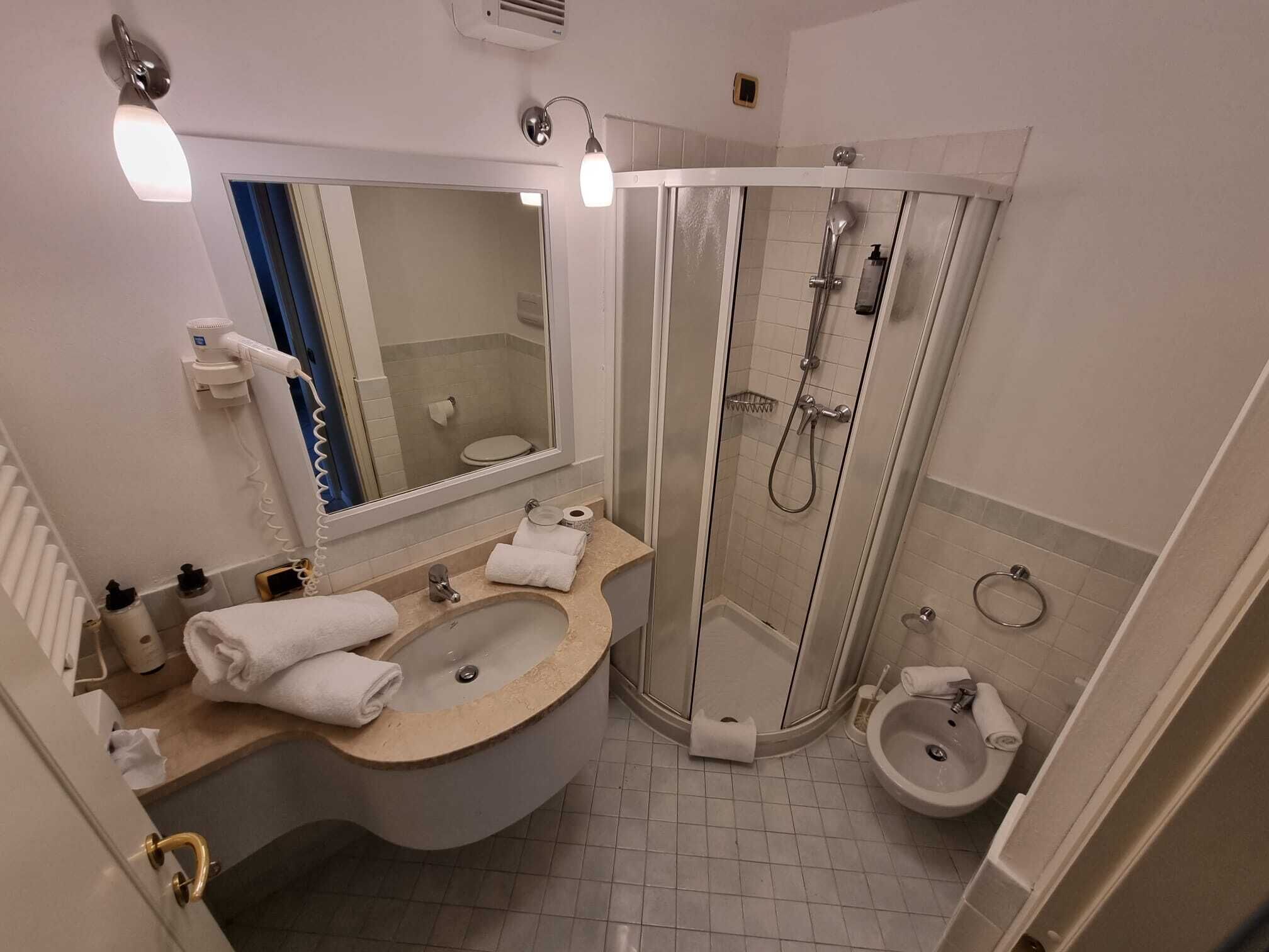 A modern bathroom with a curved sink, a shower enclosure, and a separate pedestal sink.