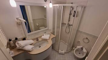 A modern bathroom with a curved sink, a shower enclosure, and a separate pedestal sink.
