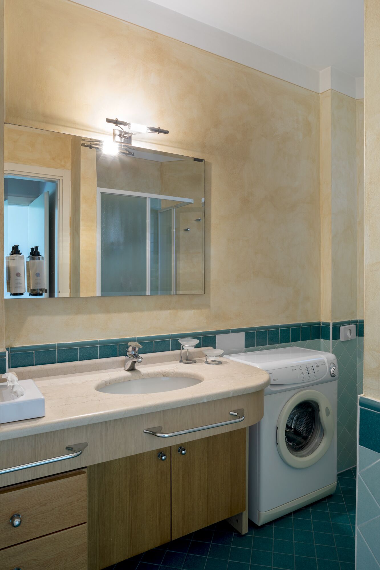 A bathroom with a sink, mirror, and washing machine.