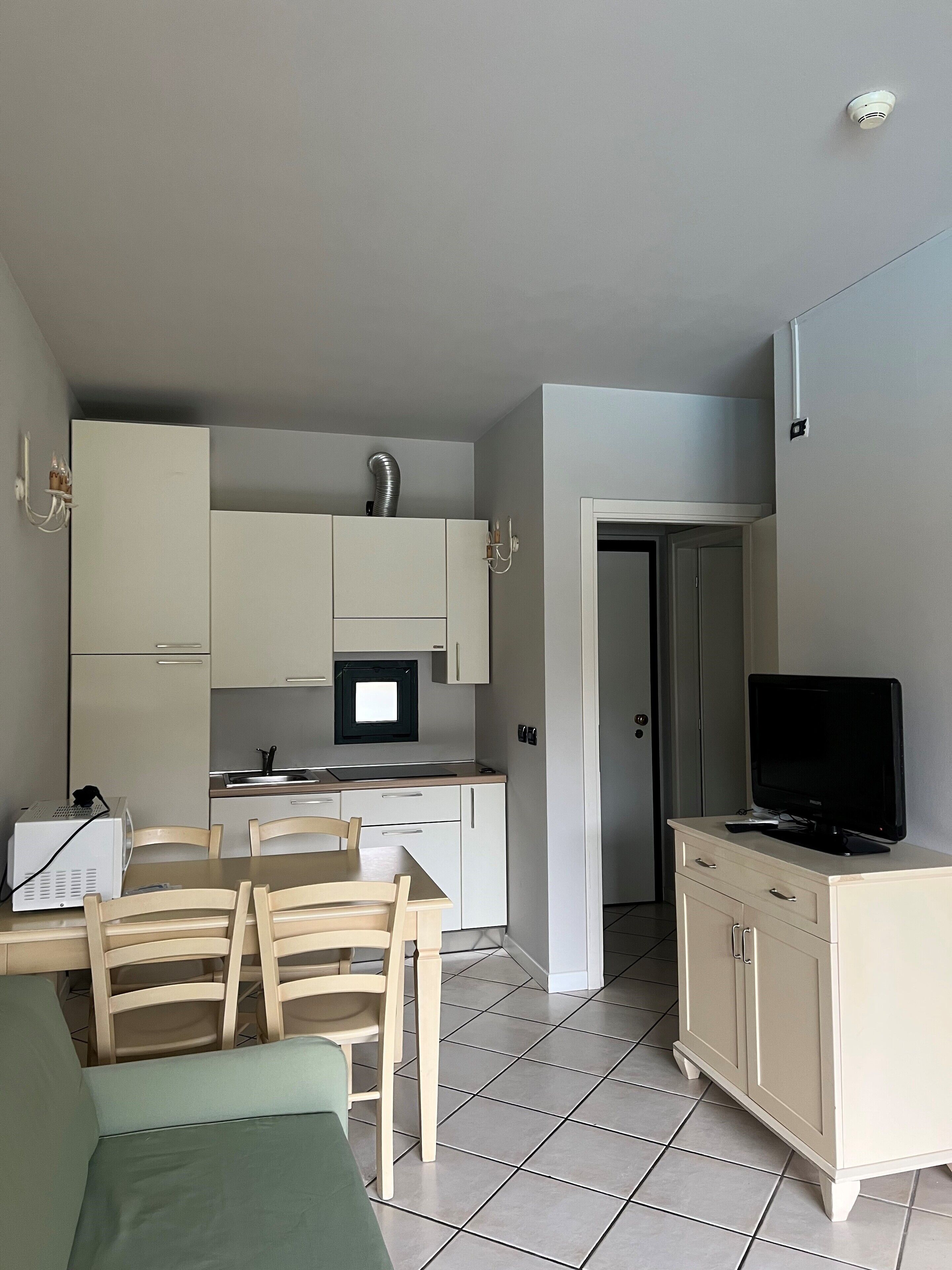 A compact living space with a kitchenette, a dining area, and a TV on a cabinet.