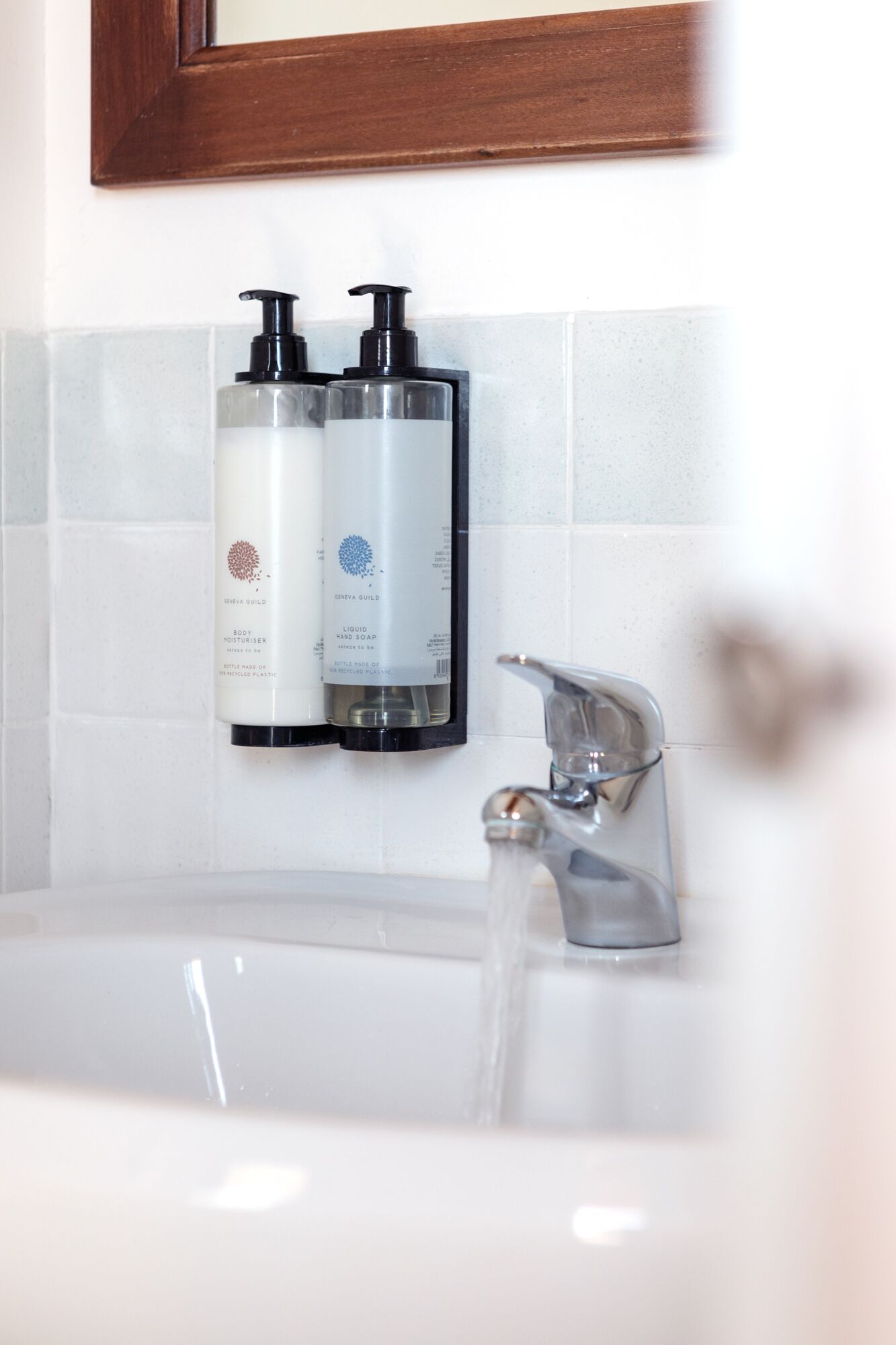 A bathroom with a white sink, two hand soap dispensers, and a faucet.