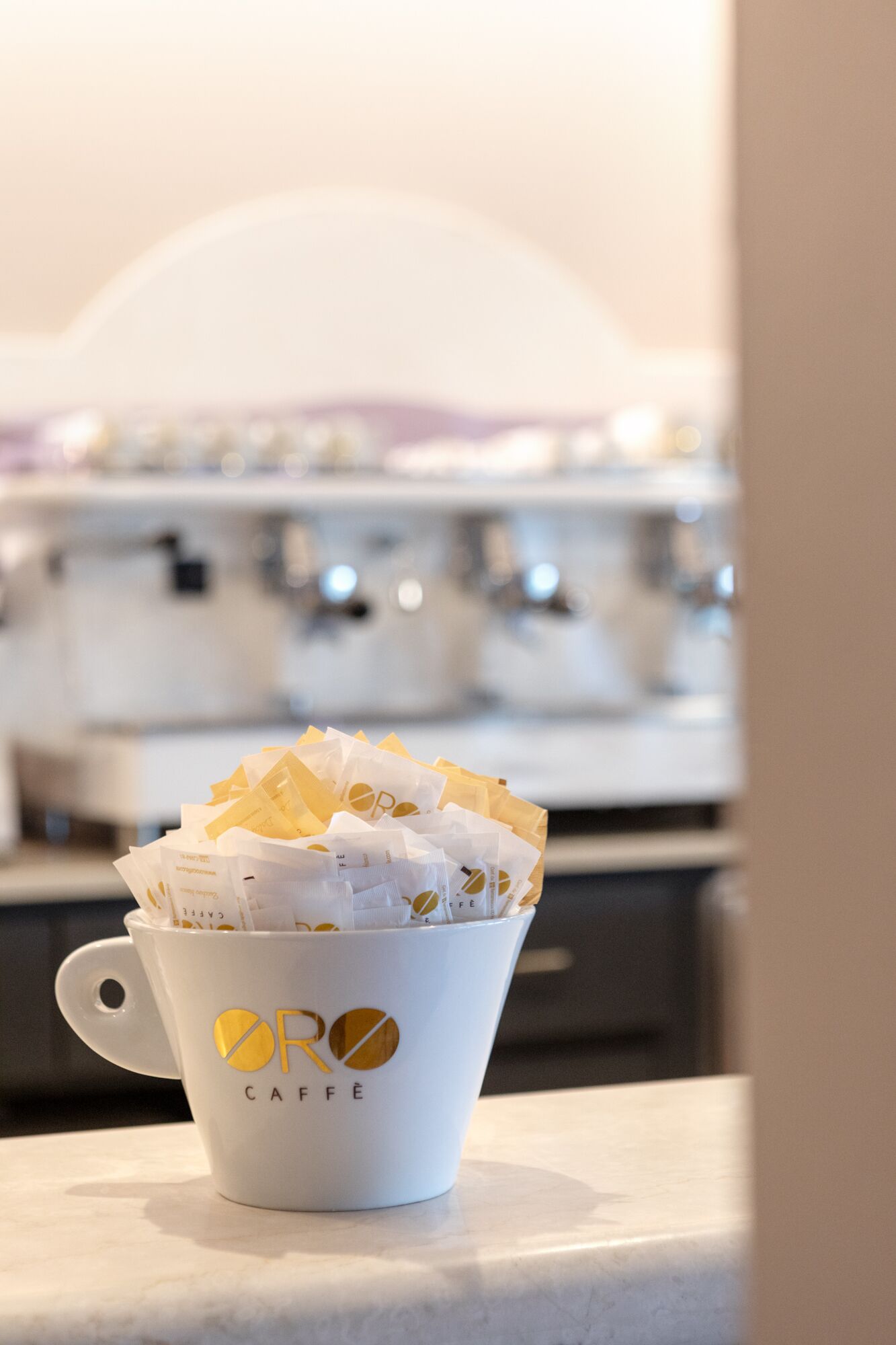 Une tasse à café blanche ornée du logo « OR Caffè », contenant des capsules de café.