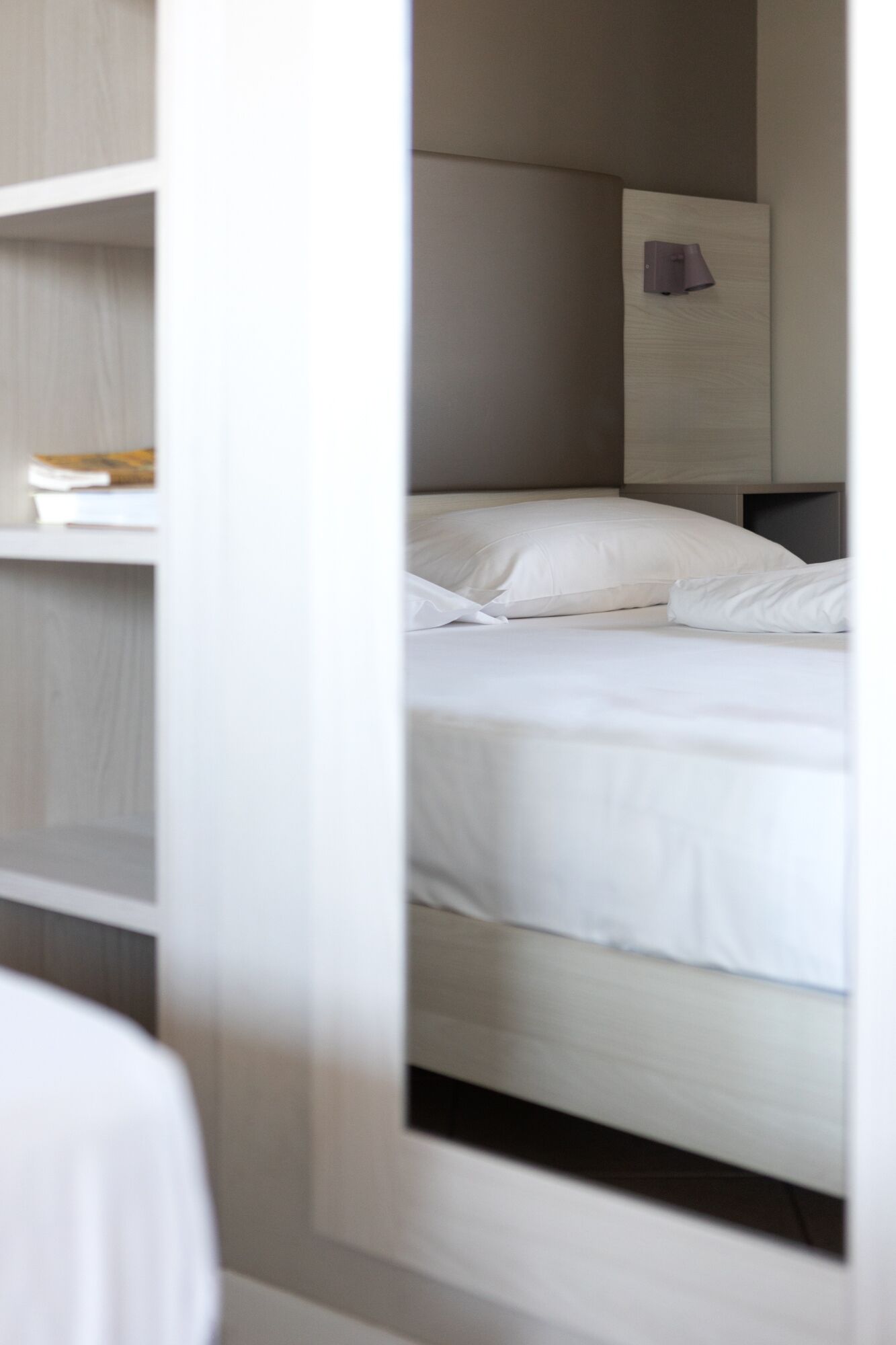 Une chambre à coucher moderne avec un lit soigneusement fait, une table de chevet et une lampe fixée au mur.