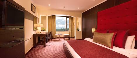 Une chambre d’hôtel avec un grand lit, un bureau, une chaise et un téléviseur.