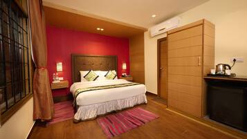 Une chambre d’hôtel avec un grand lit, une armoire en bois, un petit coin cuisine et une fenêtre avec des rideaux.