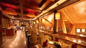 Un restaurante con interiores de madera, mesas dispuestas con servilletas rojas y vistas al exterior.