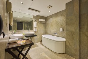 A modern bathroom with a large bathtub, a vanity with a sink, and a mirror.
