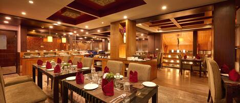 Comedor de hotel con varias mesas dispuestas para los huéspedes, equipado con sillas, mesas y cubiertos.