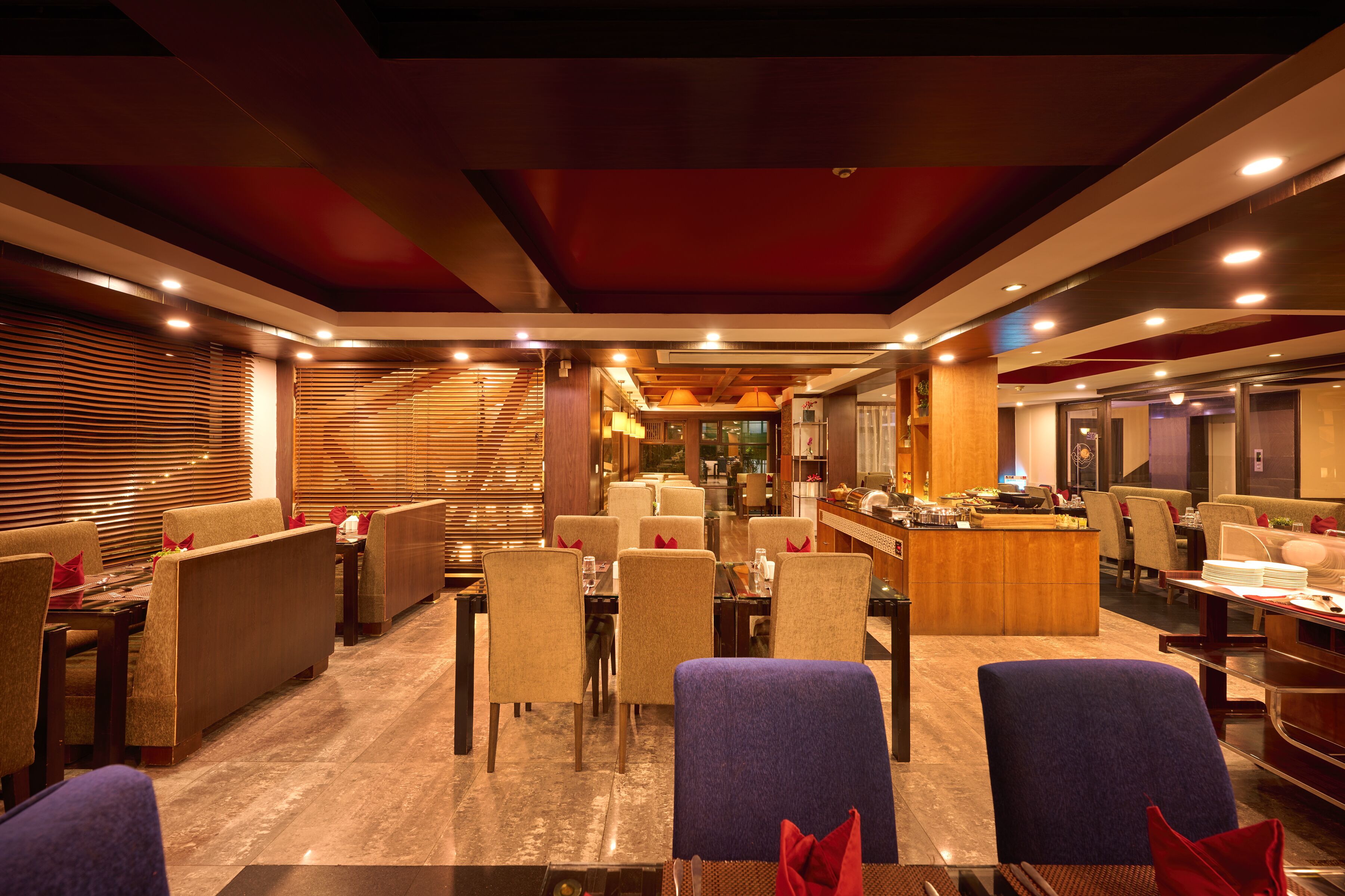 Un restaurant modern amb sostres alts, il·luminació empotrada i una combinació d'assecants i taules.