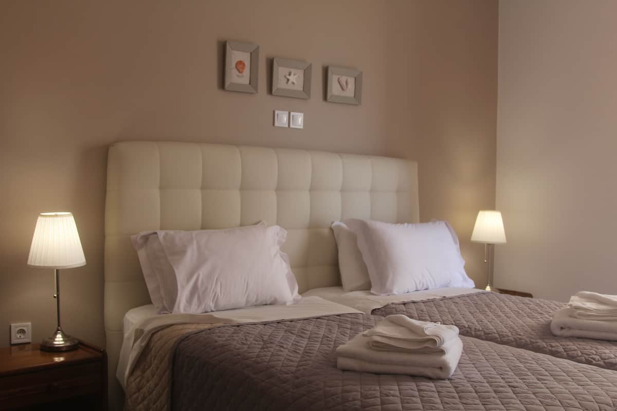 A hotel room with a large bed, two bedside lamps, and a wall with three framed pictures.