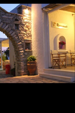 A stone building with a sign that reads "Restaurant" and a small window with a potted plant. - Scala Apartments (Naxos)