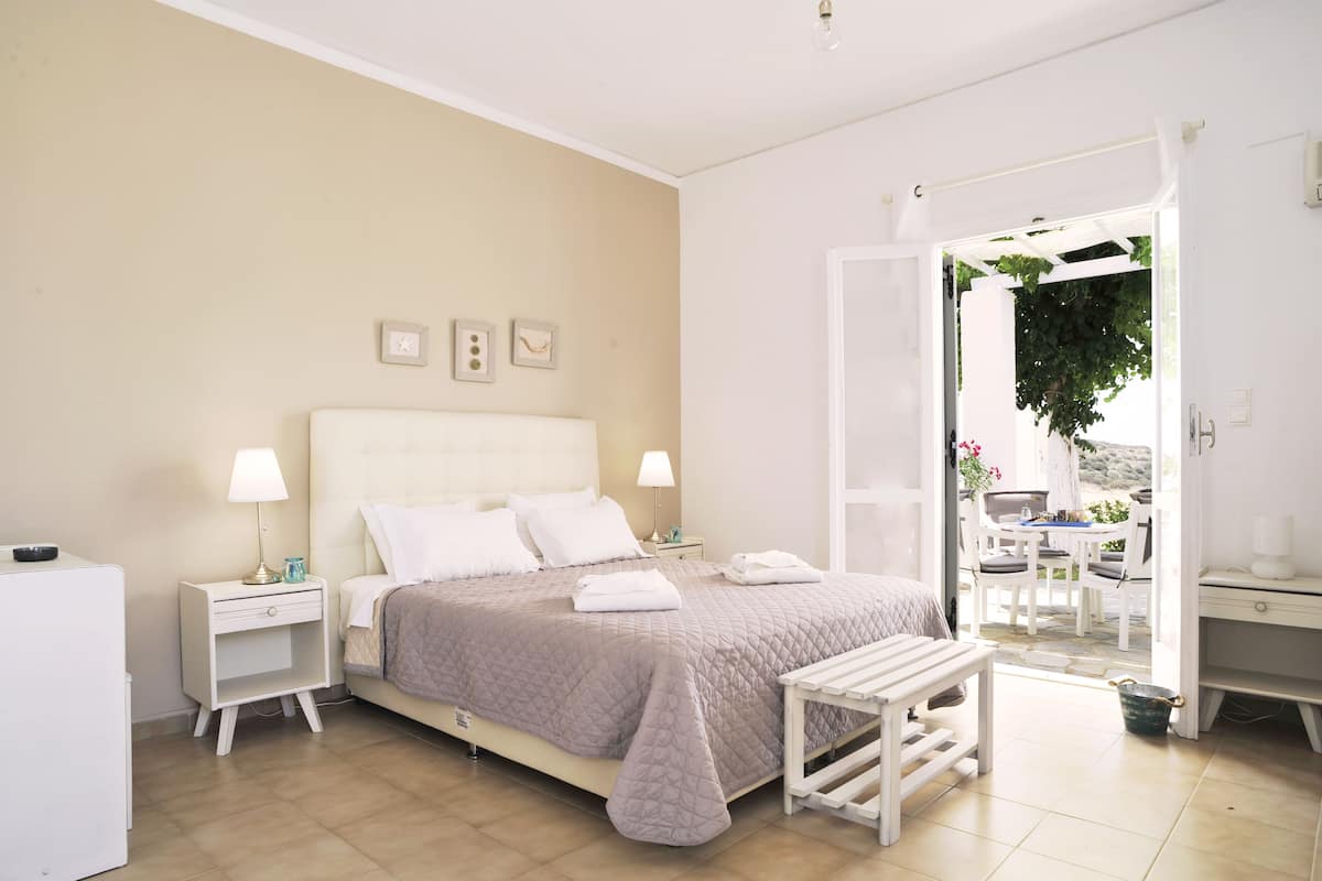 A bedroom with a bed, bedside tables, a bench, and a view of the outdoors.