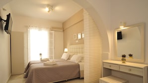 A bedroom with two beds, a vanity with a mirror, and a small table. - Scala Apartments (Naxos)