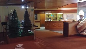 Zona de recepción con un expositor de vidrio que contiene un árbol de Navidad y un mostrador de madera.