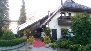 Entrada de un hotel con alfombra roja que conduce a la puerta, rodeada de follaje y un letrero que dice "HOTEL".