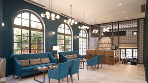 Amplia sala de estar con un sofá azul, sillones a juego, una mesa de centro y una zona de bar con taburetes.